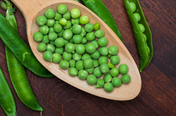 istock Green, tender, fresh and raw peas. Close-up and top view. Rustic appearance. Rustic appearance and wooden spoon. 1132825931