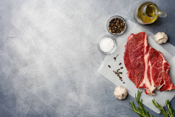istock Raw meat. Raw beef steak on with rosemary and spices. Top view copy space. 1132827323