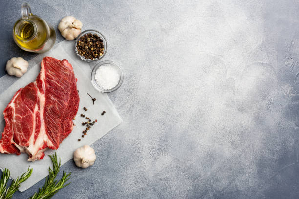 istock Raw meat. Raw beef steak on with rosemary and spices. Top view free space. 1132827331