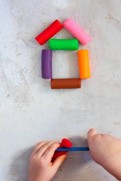 istock Colorful clay plasticine, modelling clay placed like house with child's hands, vertical, education, child psychology, neuropsychology fine motor skills manual dexterity copy space build real estate 1132827609