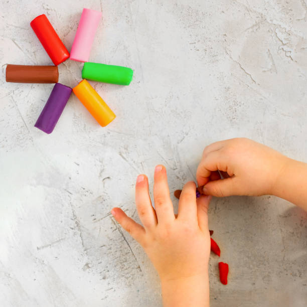 Colorful clay plasticine, modelling clay placed like flower with child's hands, square, education, child psychology, neuropsychology fine motor skills manual dexterity copy space build mental health Colorful clay plasticine, modelling clay placed like flower with child's hands, square, education, child psychology, neuropsychology fine motor skills manual dexterity copy space mental health build neuropsychology stock pictures, royalty-free photos & images