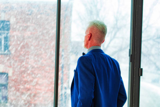 istock Mature man looking out of window watching a snow storm 1132828011