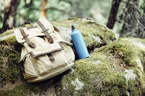 Backpack with water bottle on nature outdoor, hiking equipment.