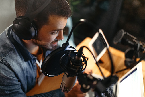 Photo of young man recording a podcast in a studio