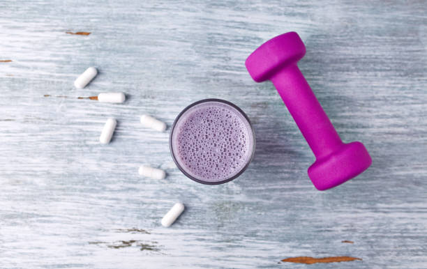 glass of protein shake with milk and blueberries. bcaa amino acids and a violet dumbbell in background. sport nutrition. rustic wooden background. top view. copy space. - vitality food food and drink berry fruit imagens e fotografias de stock