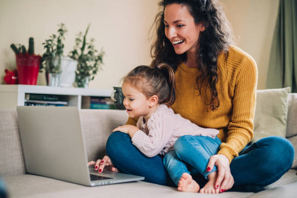 istock Mother and daughter using laptop on sofa 1132842618