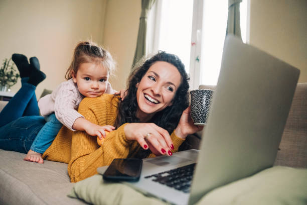 istock Mother and daughter using laptop on sofa 1132842622