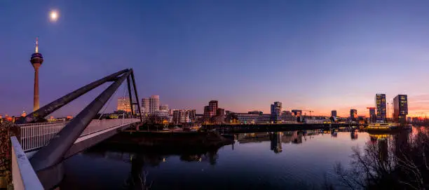 Rheinturm (Rhine Tower), footbridge over river Rhine and Skyline of Düsseldorf MedienHafen (Media Harbour) at sunset