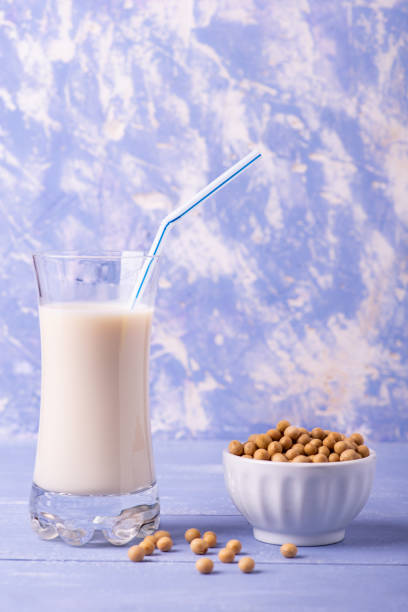 soybeans, and soy milk in the glass in the foreground on the table in light blue wood, yellow soy beans and soy milk in the glass in the foreground bicchiere stock pictures, royalty-free photos & images