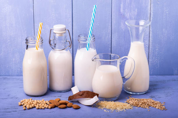 Various types of all-vegetable and organic milk in glass containers types of vegetable and organic milk in glass containers on a light blue wooden table bicchiere stock pictures, royalty-free photos & images