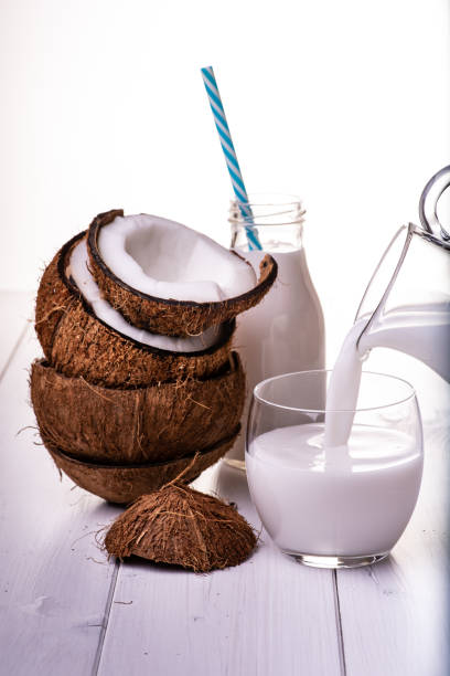 coconut and coconut milk on the table, coconut drink poured into the glass and parts of stacked coconuts bicchiere stock pictures, royalty-free photos & images