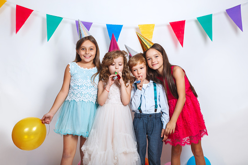 Portrait of joyful friends at birthday party with cake and props for painting.