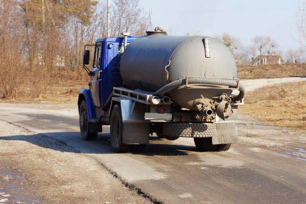 caminhão grande com um barril cinza e uma mangueira vai em uma estrada de asfalto - sewage truck - fotografias e filmes do acervo