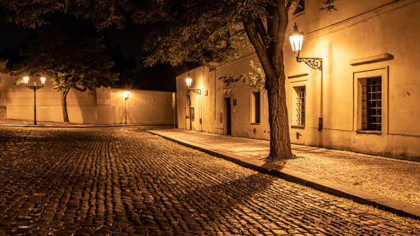 wąska brukowana ulica w starym średniowiecznym mieście z oświetlonymi domami przez zabytkowe lampy uliczne, novy svet, praga, czechy. nocny strzał - prague old door house zdjęcia i obrazy z banku zdjęć