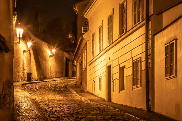 ヴィンテージストリートランプ、ノーヴィノヴィースヴィエトエリア、プラハ、チェコ共和国によって照らされた家と古い中世の町の狭い石畳の通り。ナイトショット - prague old door house ストックフォトと画像