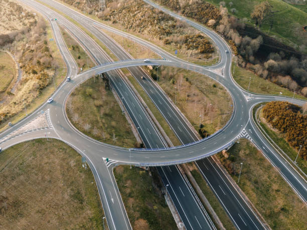 mehrere spurige autobahn mit großem kreisverkehr darüber - driving industry land vehicle multiple lane highway stock-fotos und bilder