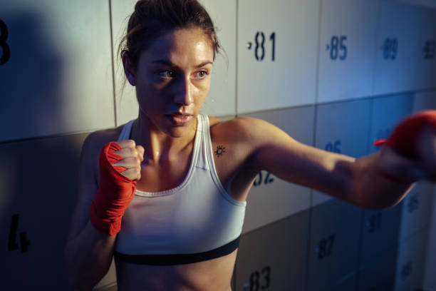 istock Determined female boxer in fighting stance at gym's dressing room. 1132870066