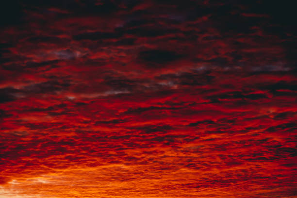 Fiery red blood vampire dawn. Amazing warm dramatic fire cloudy sky. Vivid orange sunlight. Atmospheric background of sunrise in overcast weather. Hard cloudiness. Storm clouds warning. Copy space.