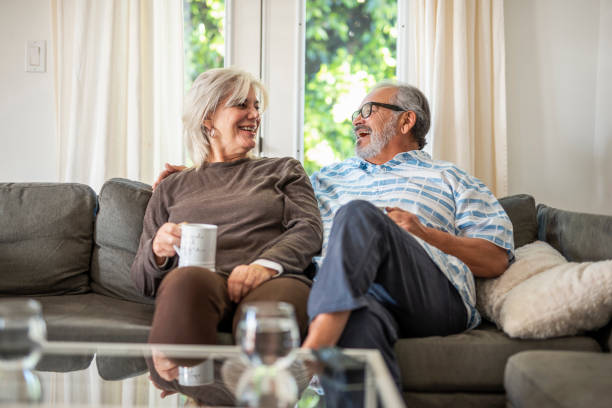Senior couple sitting on the sofa and drinking tea and laughing