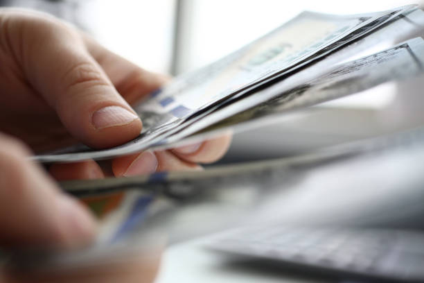 istock Male arm count hundred dollar bills closeup 1132874959