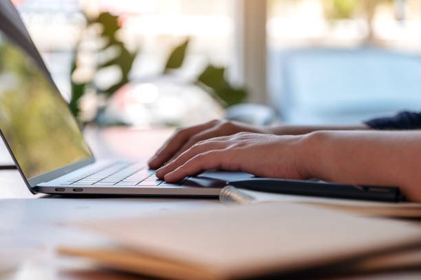 istock woman's hands using and typing on laptop with notebooks and papers on the table 1132889577
