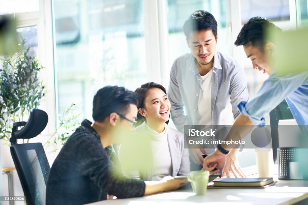 asian corporate executive meeting in office group of four happy young asian corporate executives working together meeting in office discussing business in office. Asian and Indian Ethnicities Stock Photo