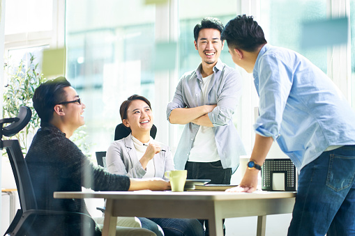Grupo de jóvenes ejecutivos de negocios asiáticos hablando en la oficina photo
