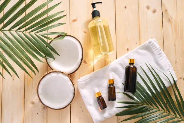 Cracked coconut and a bottle of oil on the table - spa, skincare, haircare and relaxation concept