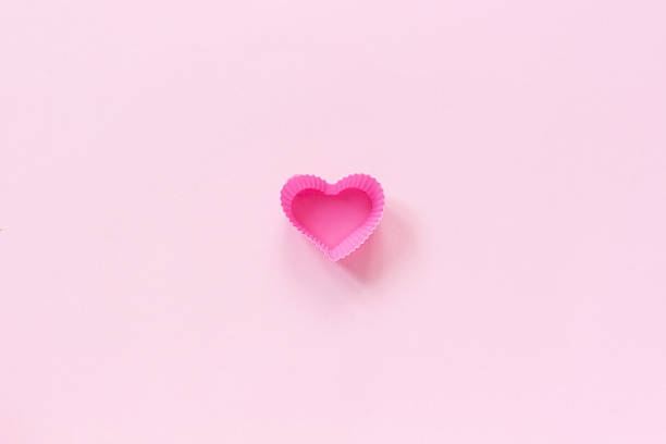 istock Silicone heart shaped mold dish for baking cupcakes on pink paper background. Template for lettering, text or your design Top view, copy space Minimal style 1132897223