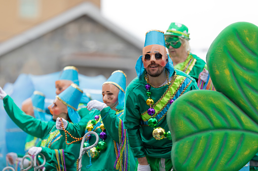 New Orleans, Louisiana, USA - February 23, 2019: Mardi Gras Parade, Men and women on top of a float using face masks and giving away beads to the spectators
