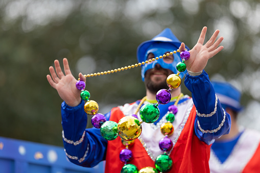 New Orleans, Louisiana, USA - February 23, 2019: Mardi Gras Parade, Man holding beads necklace on his hands, showing it to spectators