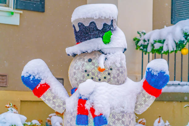 Snowman covered with snow in Daybreak Utah. Snow covered snowman on the front yard of a home in Daybreak, Utah. Porch railing lined with a snowy garland can be seen in the background.