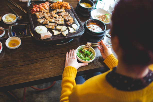 Rear View Of Caucasian Young Woman Tasting New Korean Meals