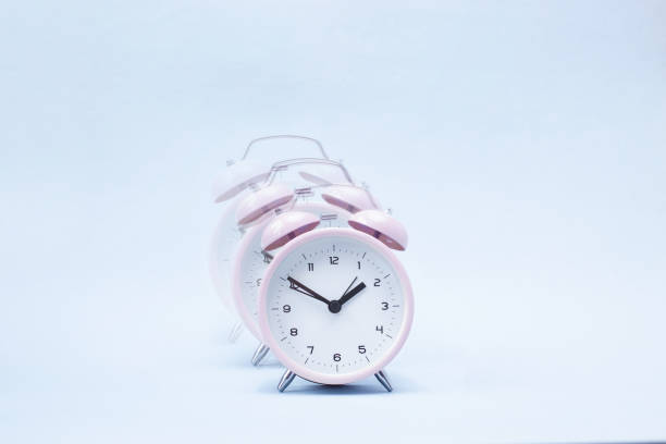 istock Pink ringing alarm clock on blue background 1132915504