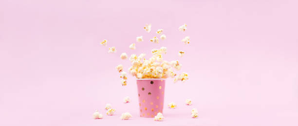 istock Flying Popcorn in a bright glass and on a pink background. 1132915505