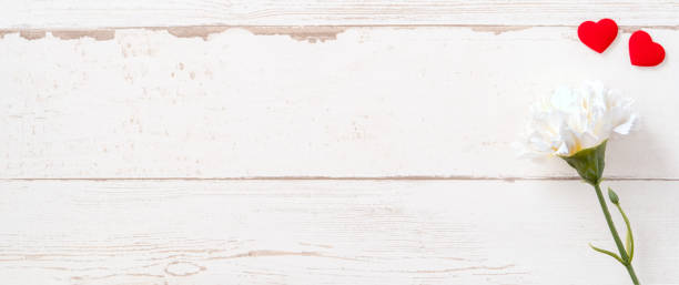 istock May mothers day concept photography - Beautiful carnations and hearts shape with white empty card isolated on a bright wooden table, copy space, flat lay, top view, mock up 1132916193