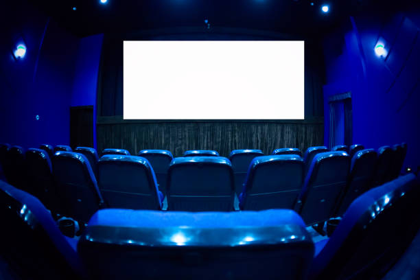istock Empty cinema auditorium with empty white screen. Empty rows of theater or movie seats. Blue toned. 1132916733