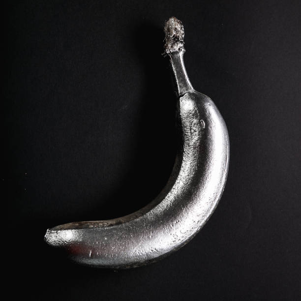 Artistic way of photographing a banana with silver spray on a black background.