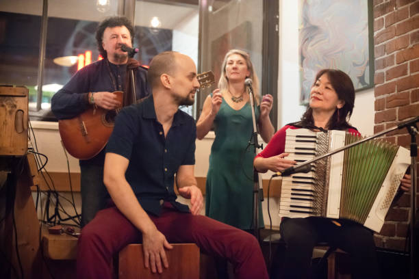 Multi-Ethnic Musicians Singing, Playing Guitar, Accordian, Peruvian Cajon in Cafe Live band performance in Vancouver, British Columbia, Canada accordion instrument stock pictures, royalty-free photos & images