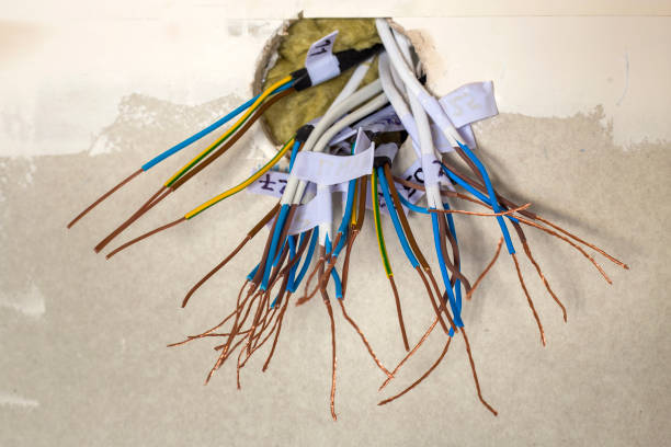 istock Electrical exposed connected wires protruding from socket on white wall. Electrical wiring installation. Finishing works in renovated apartment. 1132922688