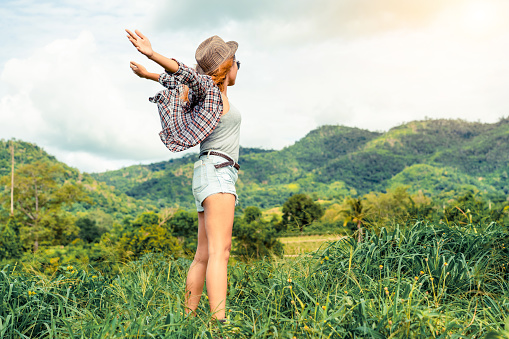 Happy woman in green field and mountain background. Freedom and travel concept.