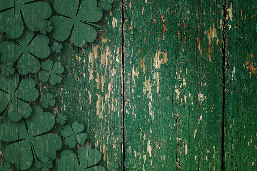 Green wooden four leaf shamrocks on wooden board