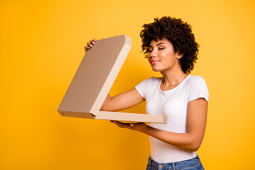 Portrait of her she nice cute lovely pretty beautiful cheerful dreamy wavy-haired lady holding in hands carton pizza box smelling isolated over bright vivid shine background.