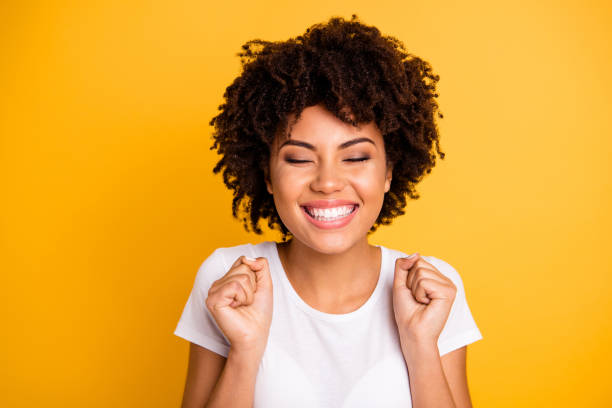 close up photo beautiful amazing she her dark skin lady hands arms fists raised eyes closed great big win competition wear casual white t-shirt isolated yellow bright vibrant vivid background - happy faces imagens e fotografias de stock