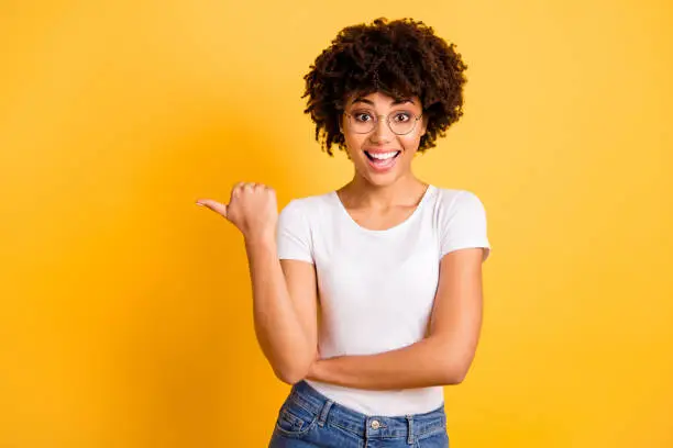 Photo of Portrait of her she nice cute smart clever attractive beautiful cheerful wavy-haired lady eyeglasses eyewear pointing aside ad advert copy space isolated over bright vivid shine background