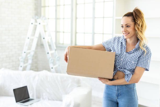 istock Smiling woman unpacking boxes in new home 1132928508