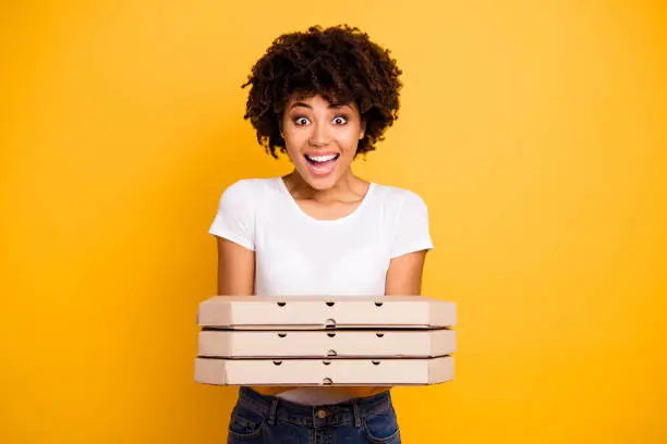 Portrait of her she nice cute lovely charming attractive beautiful cheerful wavy-haired lady holding in hands showing three carton pizza boxes isolated over bright vivid shine background.