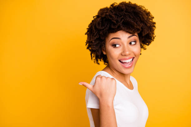 close up photo beautiful pretty amazing she her dark skin lady arm finger point picking funny funky eyes look side laugh laughter wearing casual white t-shirt isolated yellow bright vivid background - blank sale young women one young woman only imagens e fotografias de stock