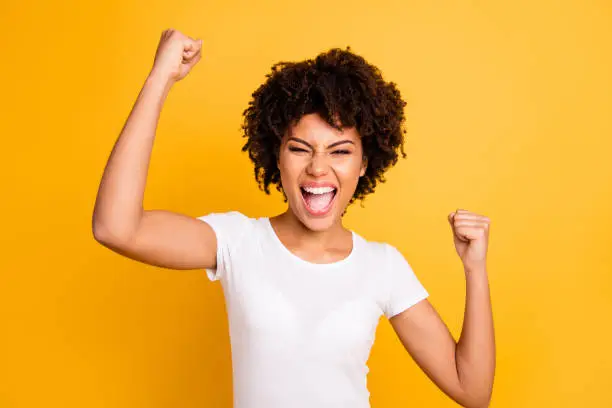 Photo of Close up photo beautiful amazing she her dark skin lady yelling loud glad hands arms fists raised great big win competition wear casual white t-shirt isolated yellow bright vibrant vivid background
