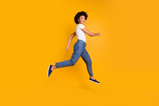 Full length body size side profile photo jumping high beautiful she her lady rushing black friday sale shopping store mall wearing casual jeans denim white t-shirt clothes isolated yellow background.
